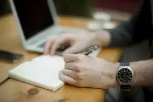a man taking notes in front of a laptop 