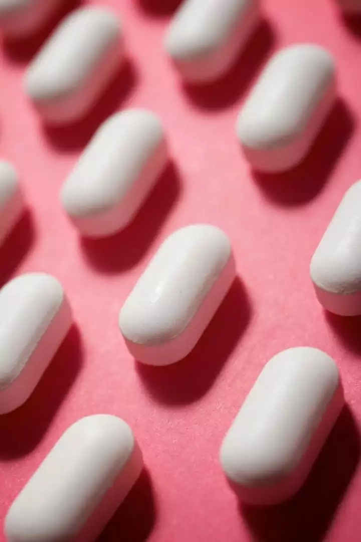 frontal shot of white oval shaped pills on a pink background