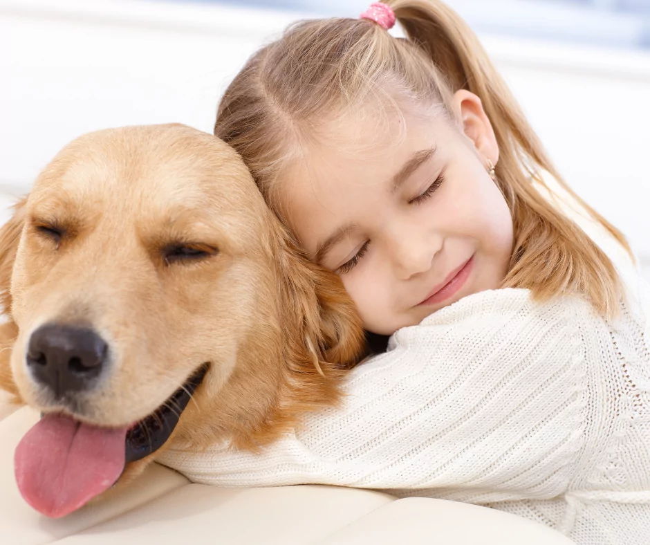 little girl with pigtails hugging her labrador retriever